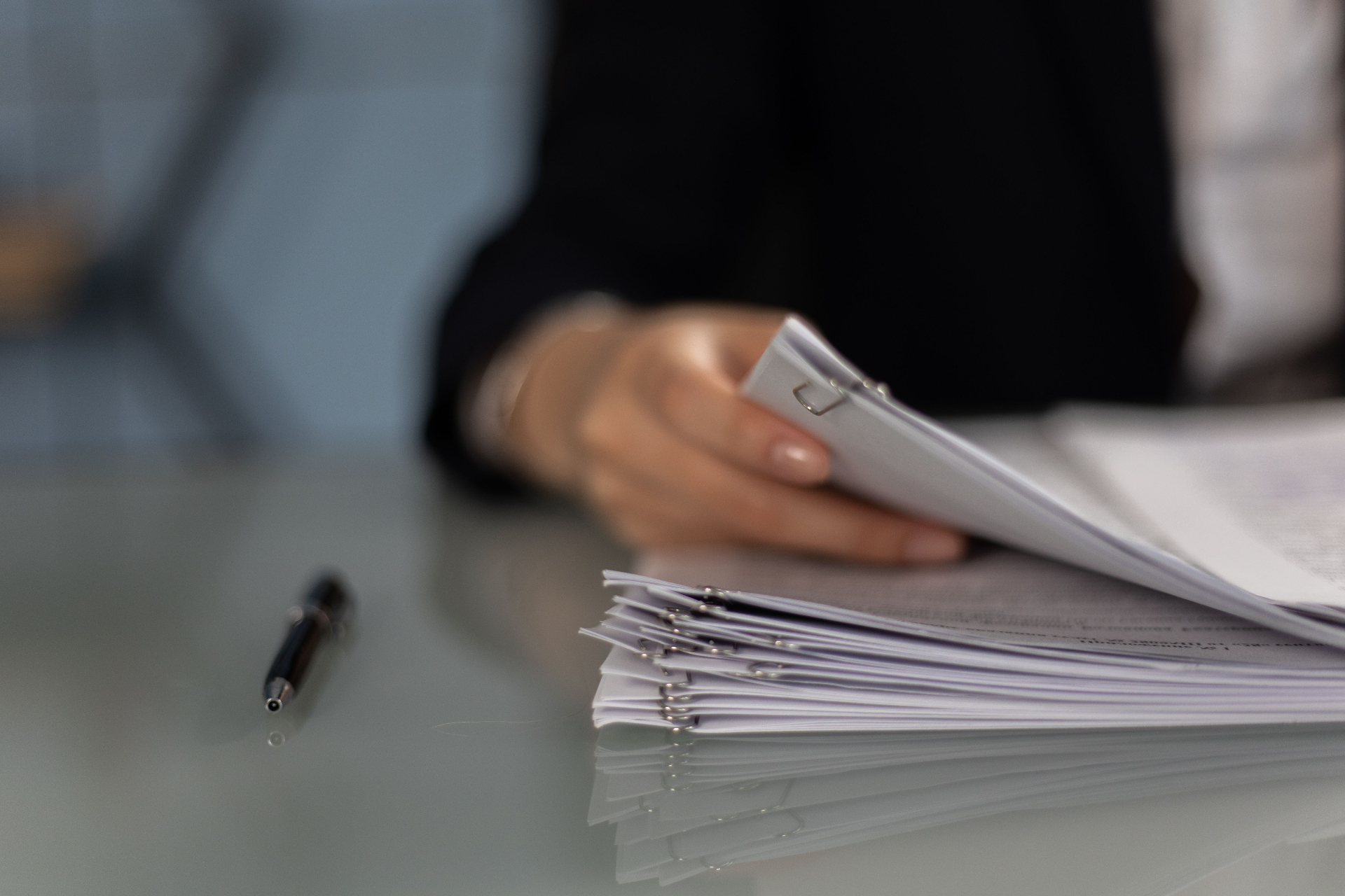 Platform reageert niet op verwijderingsverzoek, hand met stapel documenten en pen op bureau symboliseert formele dossiervorming